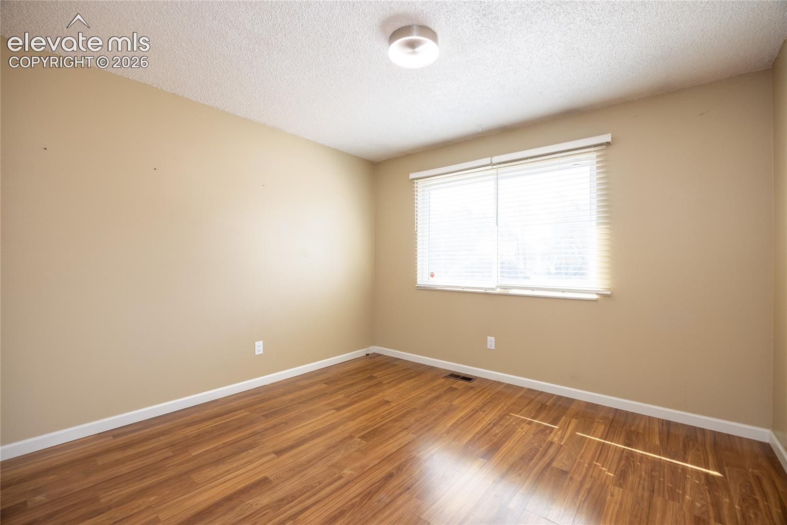 Wood-finish flooring, neutral wall paint, and a white ceiling