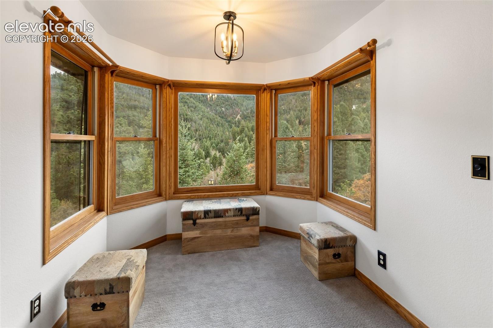 Bay window featuring wood-framed windows, integrated metal-frame ceiling fixture, and mountain backdrop