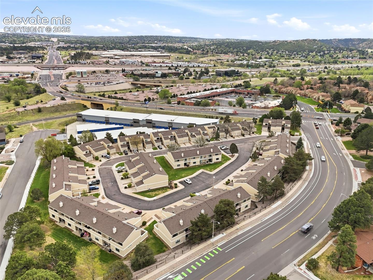 Aerial perspective of a multi-unit residential community featuring uniform building exteriors, pitched roofs, and manicured landscaping