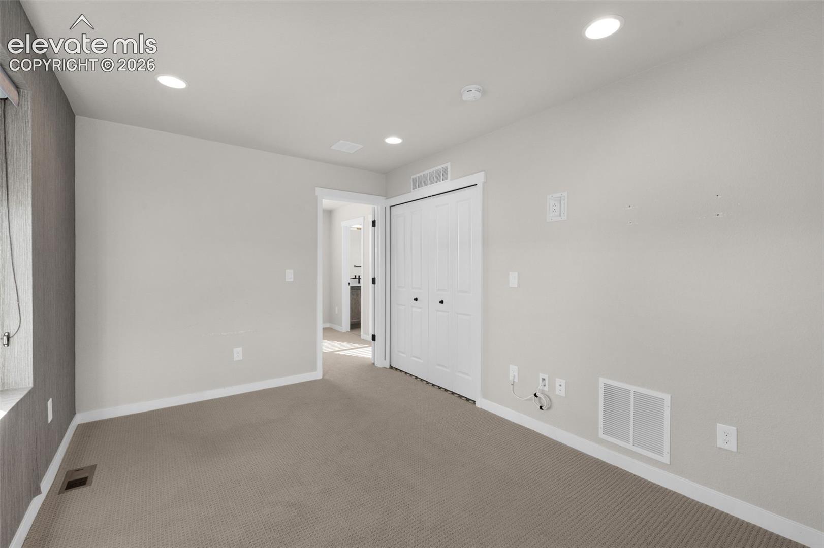 Recessed ceiling lighting illuminates the room with neutral-toned carpeting