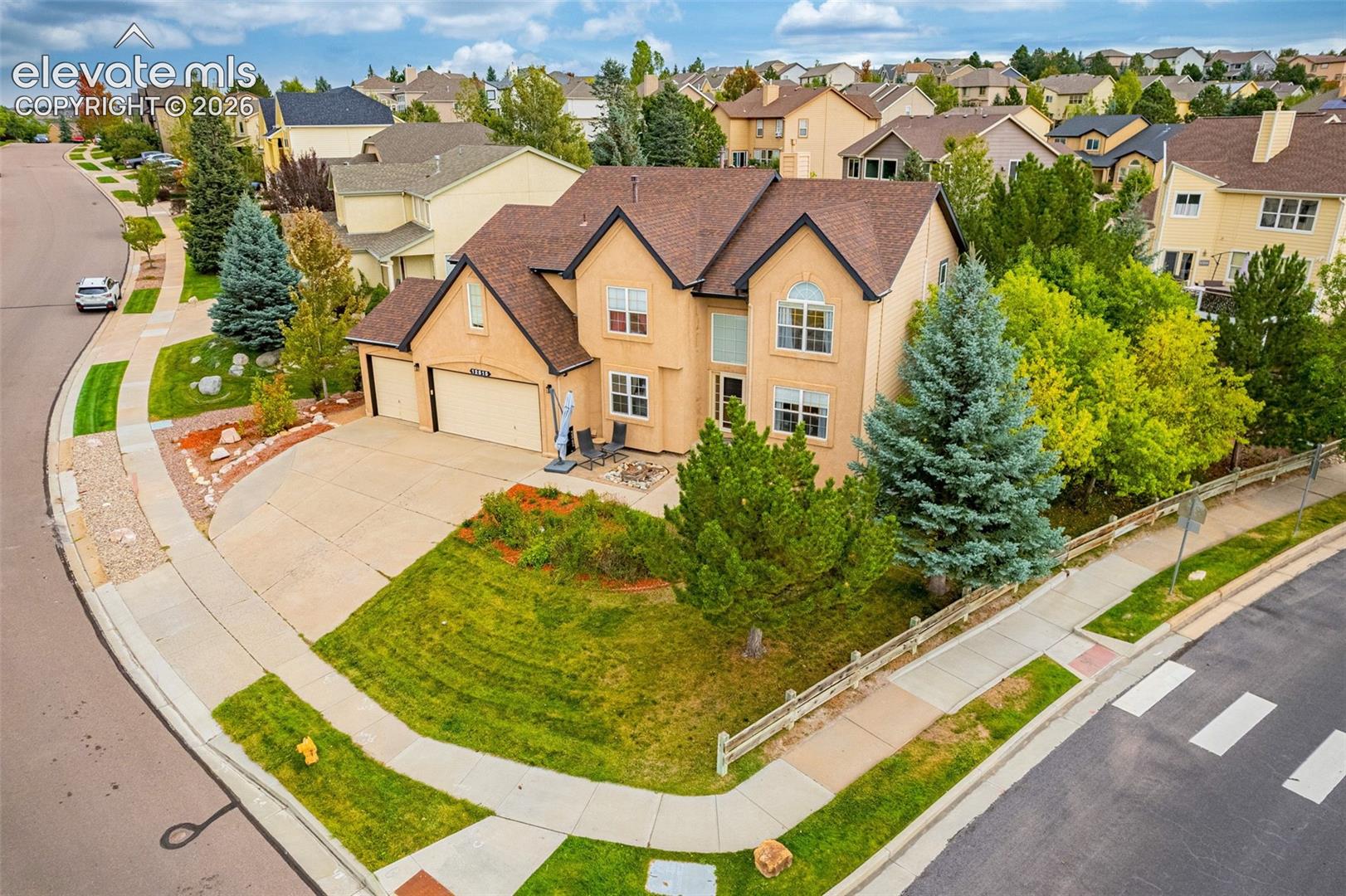 Two-story stucco exterior with an attached two-car garage, concrete driveway, and established landscaping