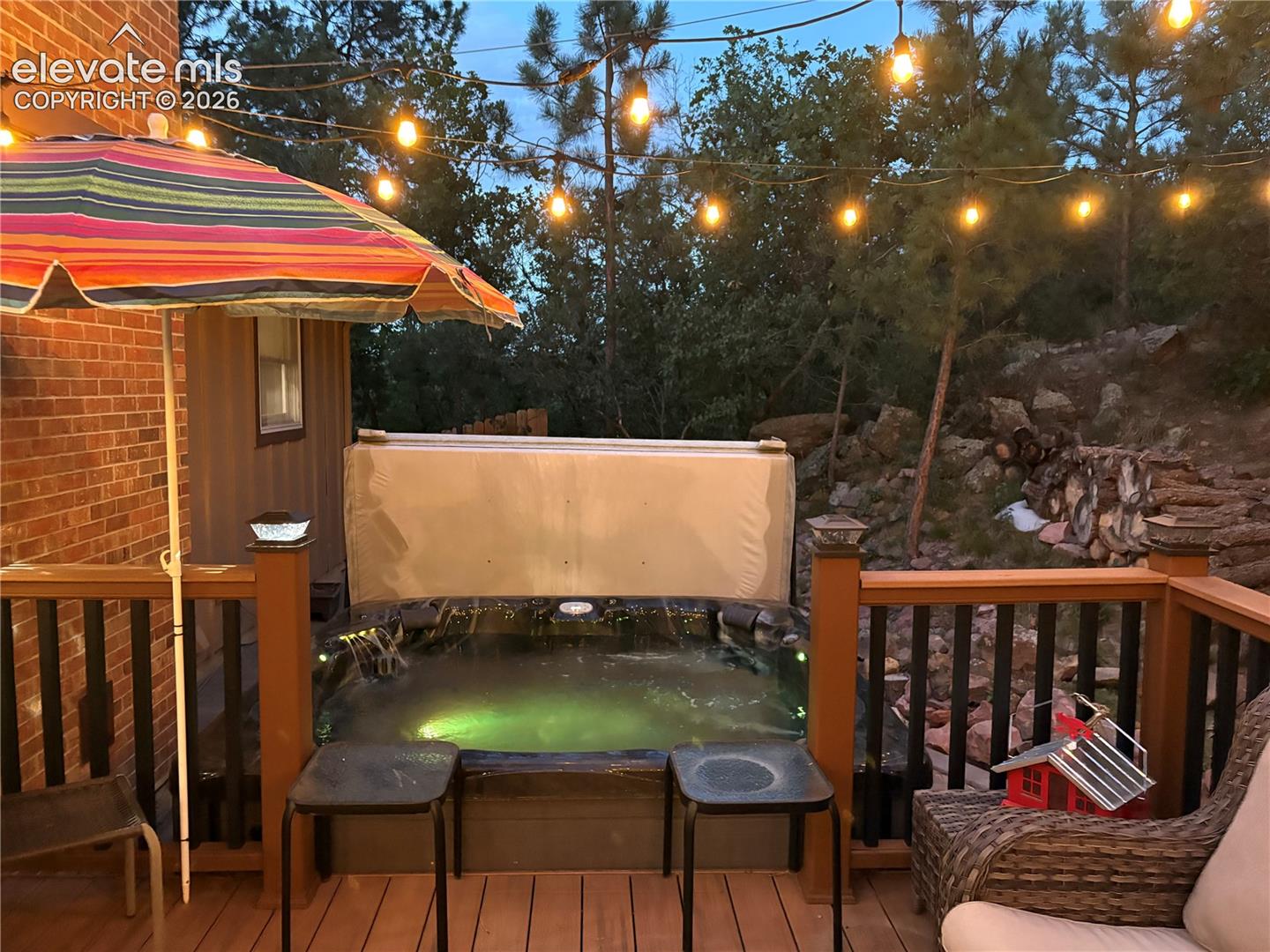 Outdoor composite deck featuring a built-in hot tub, string lighting, in a gorgeous setting