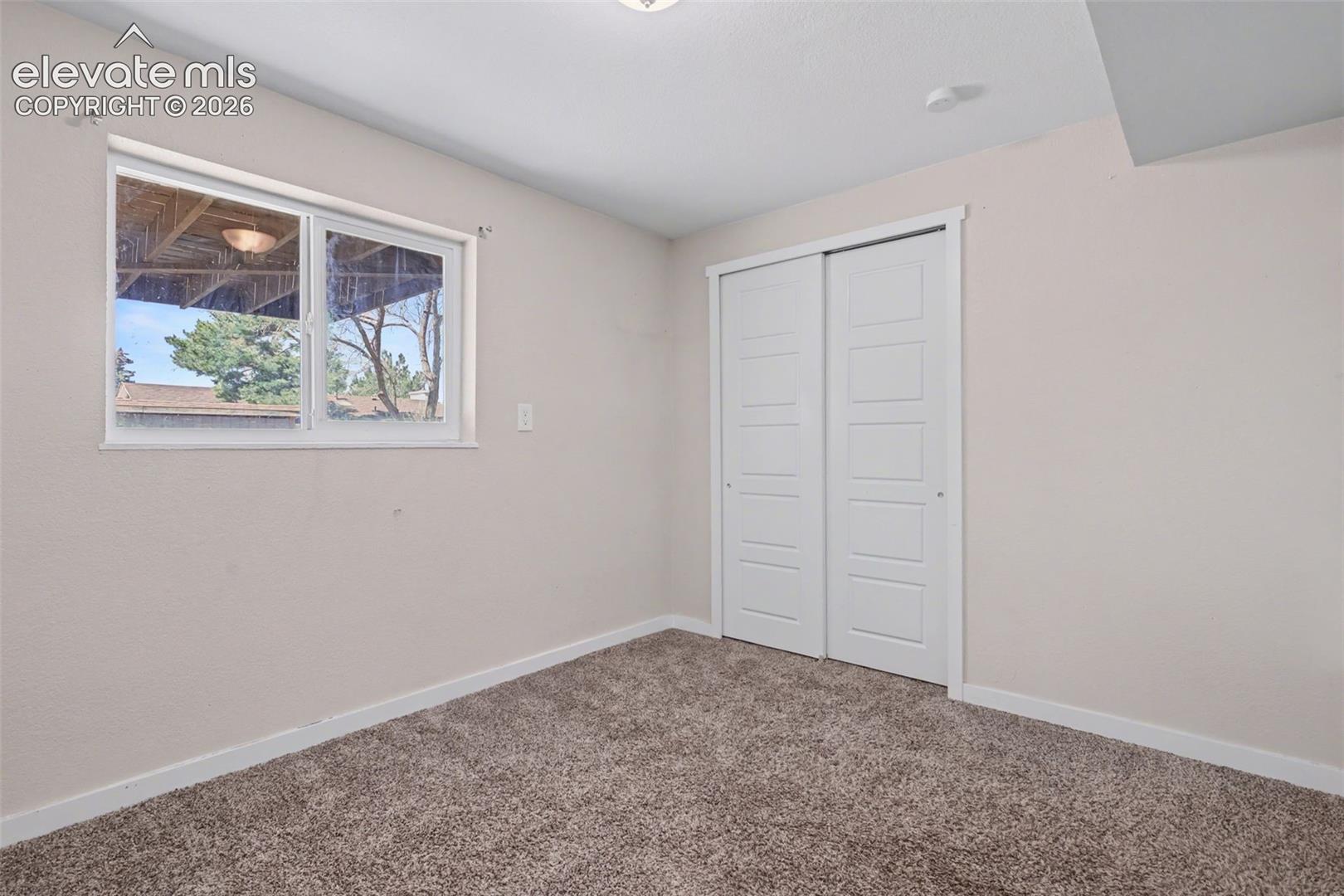 Neutral-toned room featuring wall-to-wall carpeting, a sliding-panel closet with white trim, and a horizontal sliding window