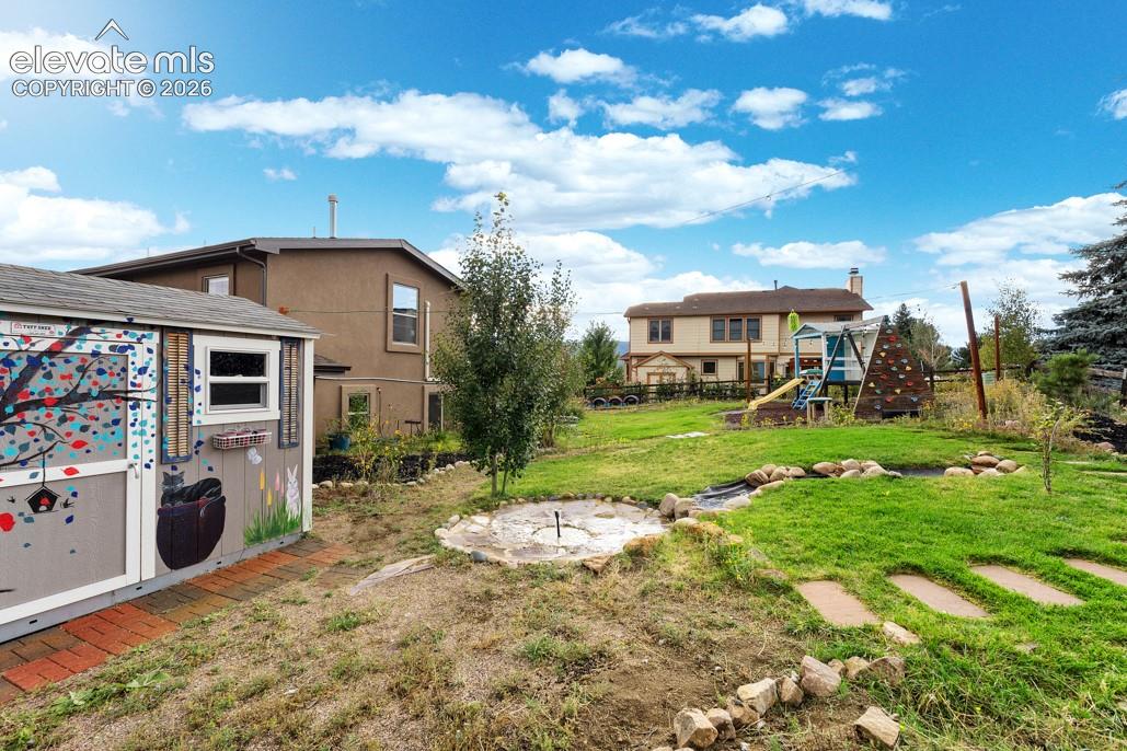Expansive backyard featuring a manicured lawn, established trees, and a decorative storage shed