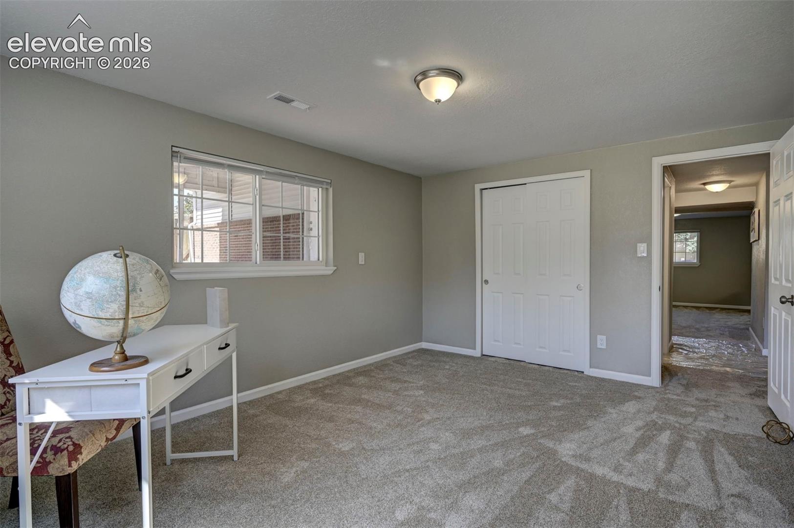 Room featuring neutral wall tones, wall-to-wall carpeting, sliding-door closet, and double-pane window with grid inserts