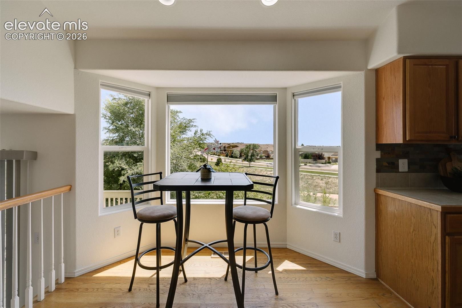 Bay window with three distinct panels, wood-finish flooring, recessed lighting, and a light wood railing