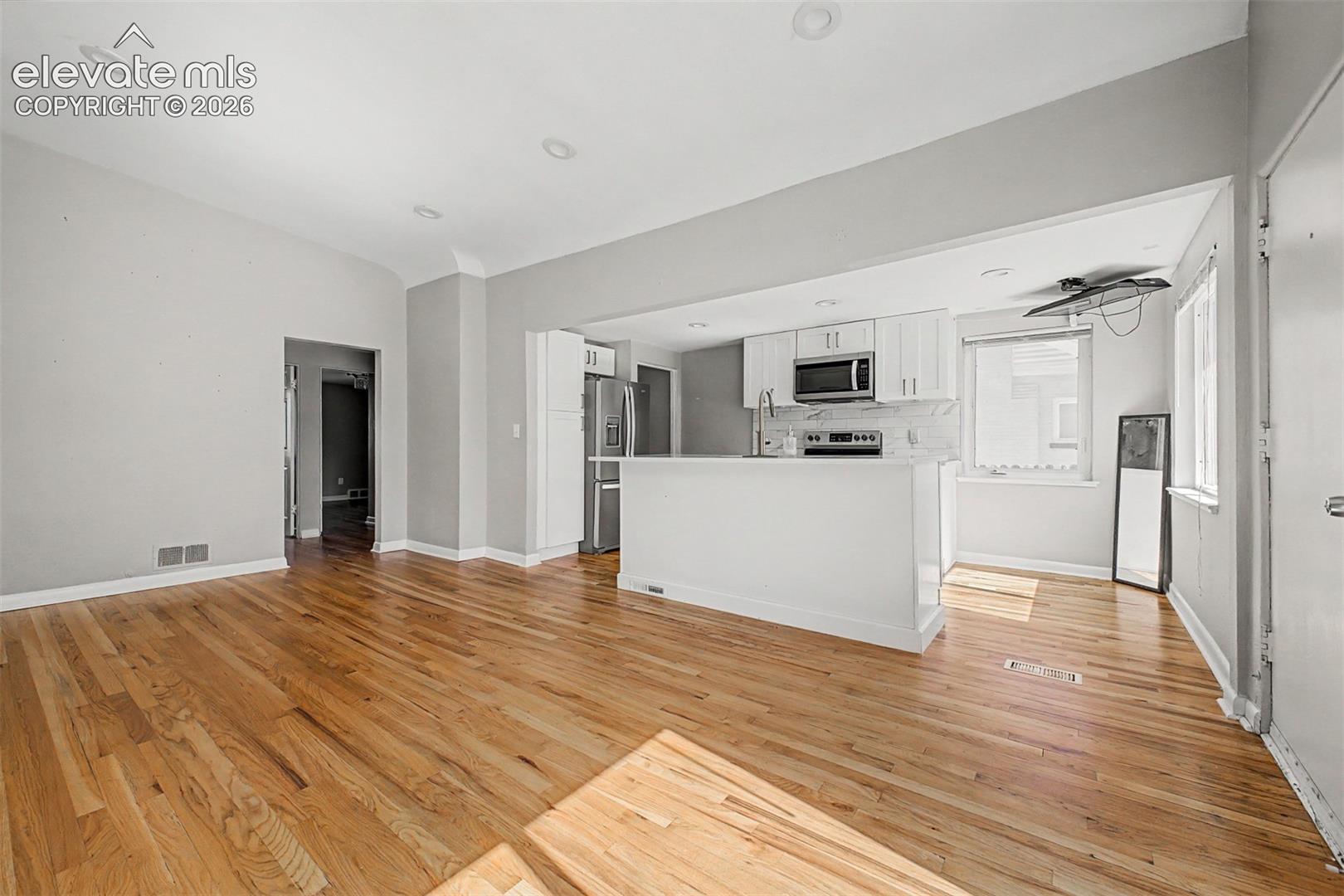 Open-concept living space featuring wood-finish flooring, recessed lighting, and light gray walls