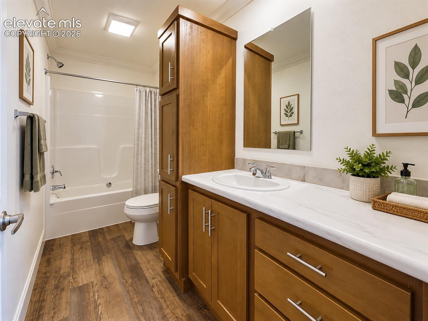 Full Bathroom – Full bath features a tub/shower combination, warm wood cabinetry, generous vanity counter space, and coordinating wood-look flooring.