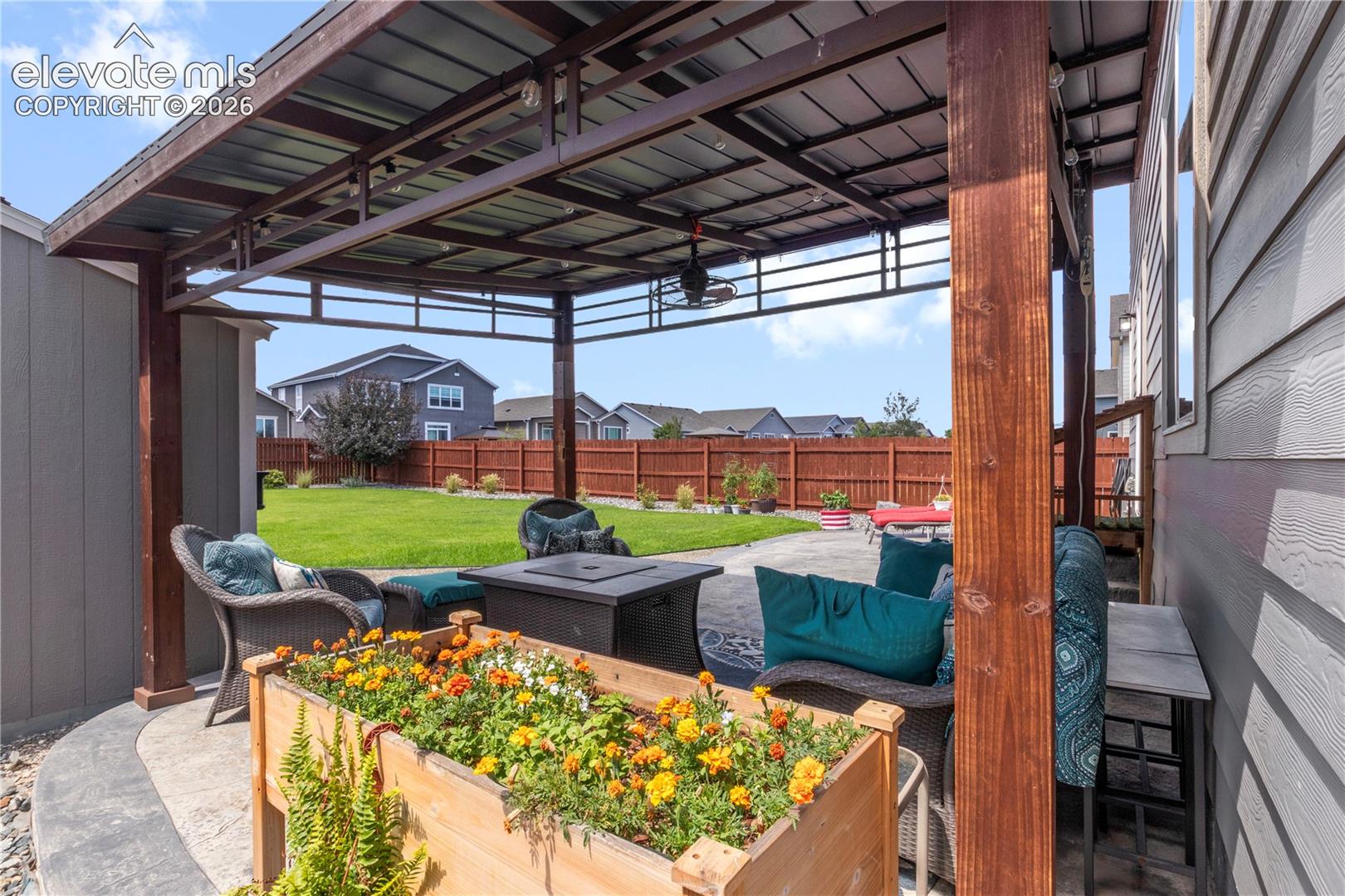 Metal-roofed patio cover with wood posts, concrete patio, and fenced yard