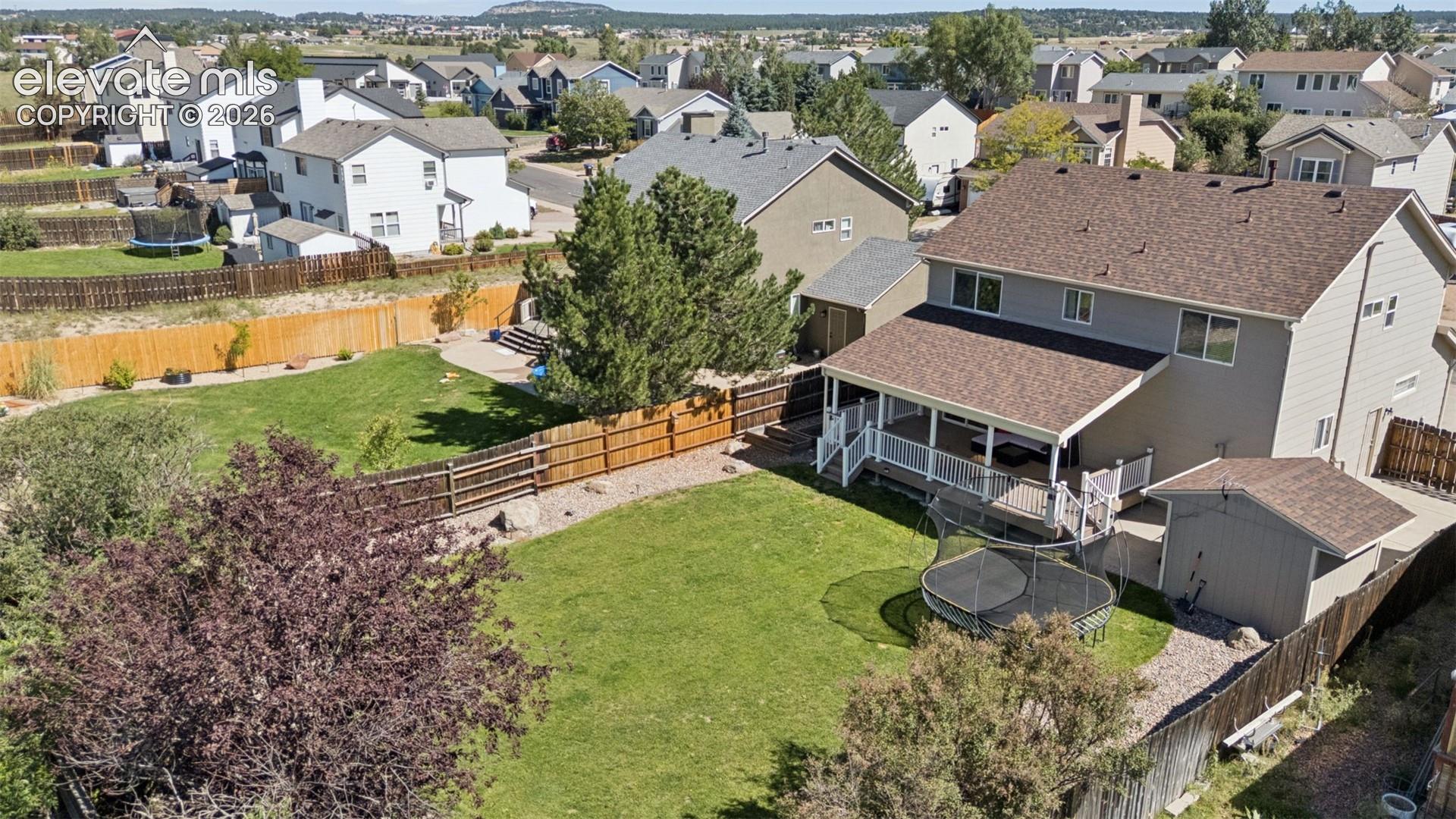 Expansive backyard with a covered deck, separate outdoor shed, and a privacy fence