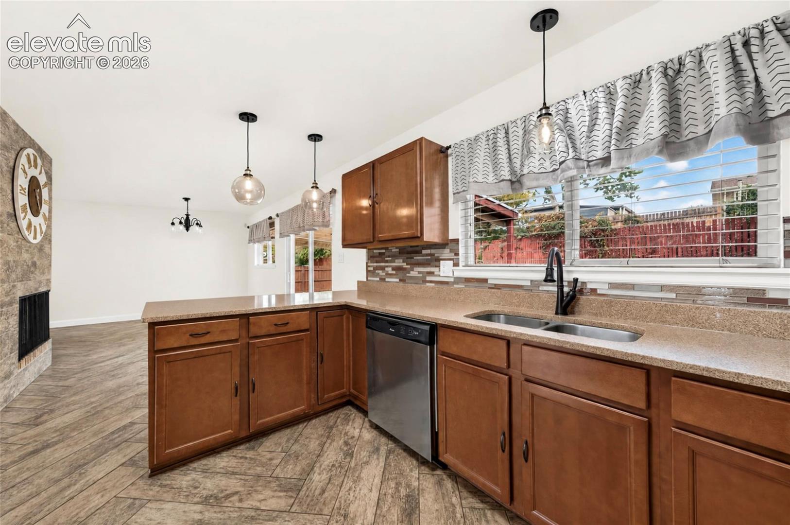 Kitchen featuring wood cabinetry, stone-finish countertops, stainless steel dishwasher, tile backsplash, and wood-finish flooring