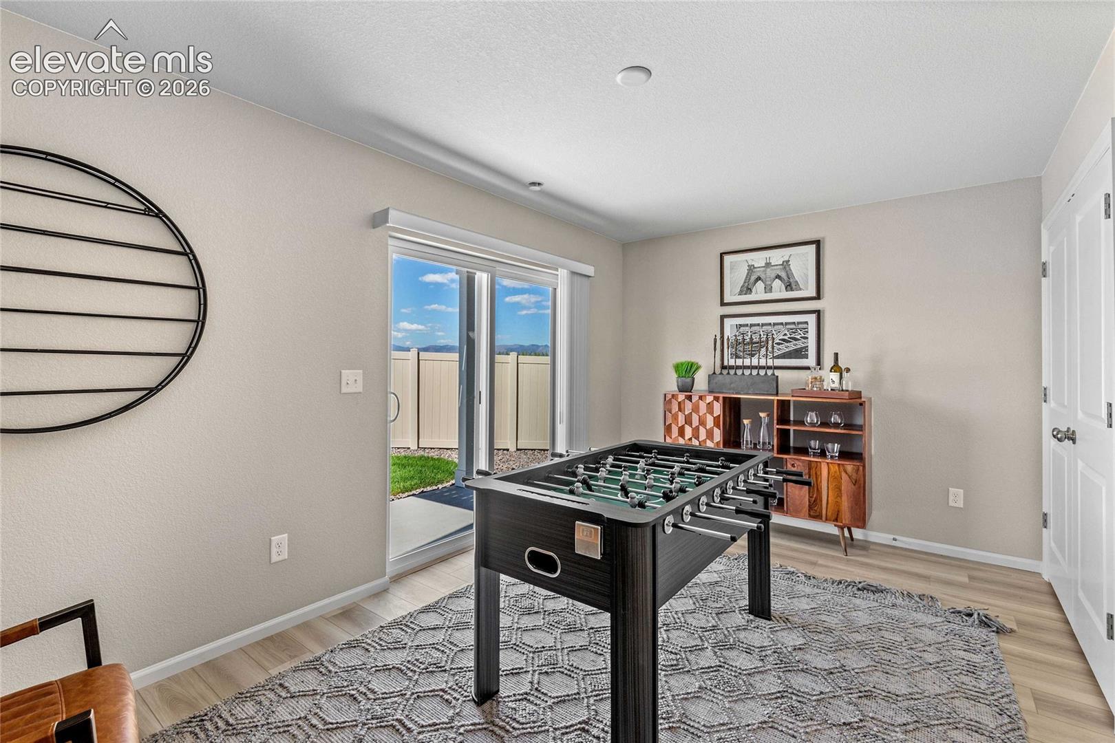 Sliding glass door opening to an outdoor patio with artificial turf, complemented by light-toned wood-finish flooring indoors
*photos of a model home*