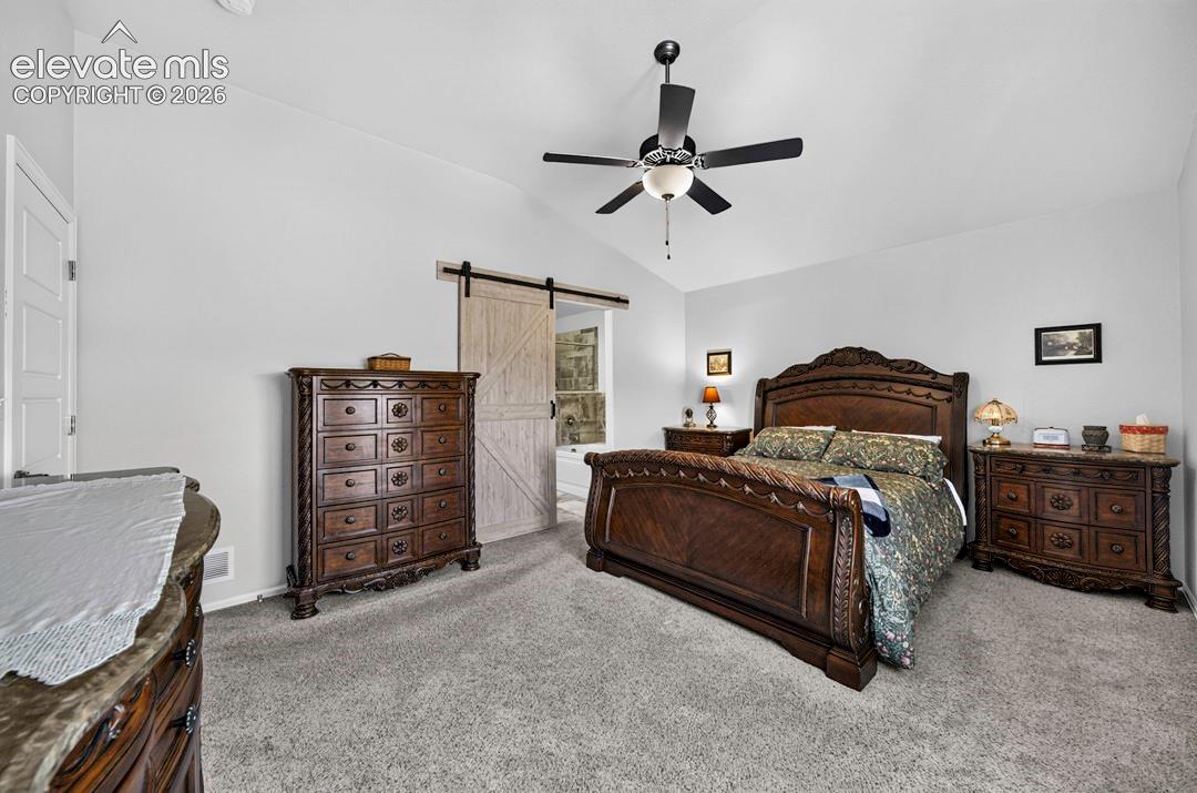 MB featuring a vaulted ceiling with a ceiling fan, a white barn door, and a white interior door