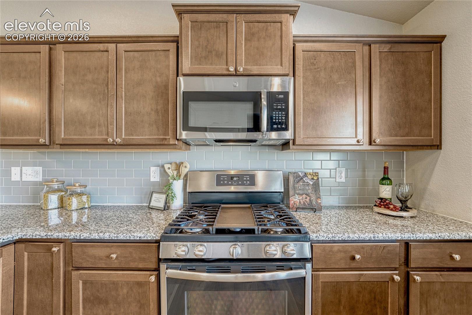 Cooking and entertaining are made easy with a modern kitchen layout featuring granite surfaces, gas range, built-in microwave oven and under-cabinet lighting.
