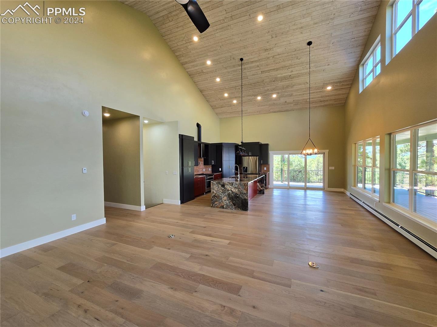 Living room featuring high vaulted ceiling, open kitchen/dining, and light hardwood / wood-style floors