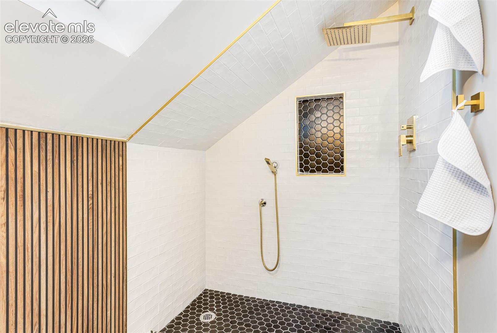 Built-in shower featuring a rain shower head, handheld shower fixture, and a recessed hexagonal tile niche
