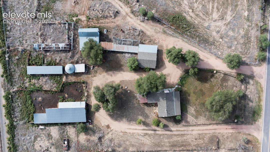 Multiple structures on expansive lot, including a primary residence with a gabled roof, two large outbuildings with metal roofs, and a grain bin