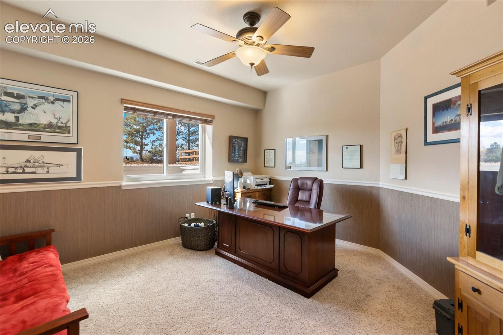Room featuring two-tone wall finish, carpeted flooring, window with exterior landscape exposure, and ceiling-mounted light fixture with fan
