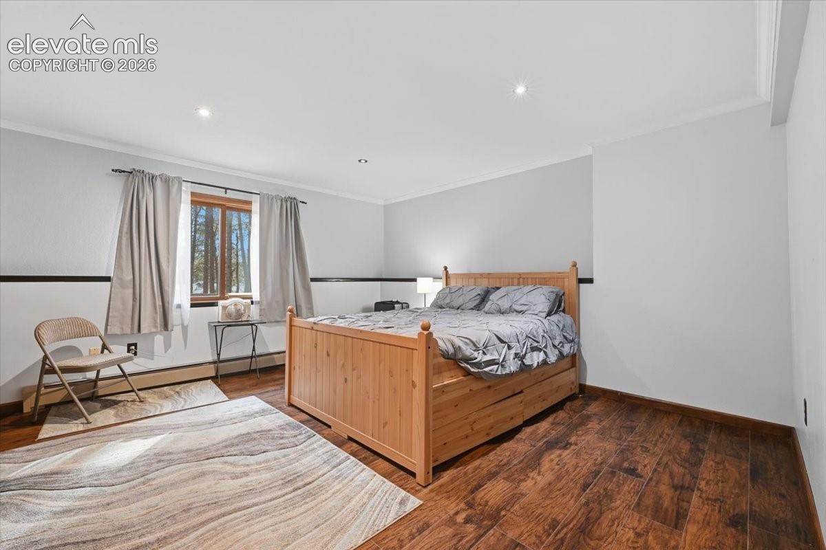 Hardwood-finish flooring, recessed lighting, crown molding, and a window with natural light