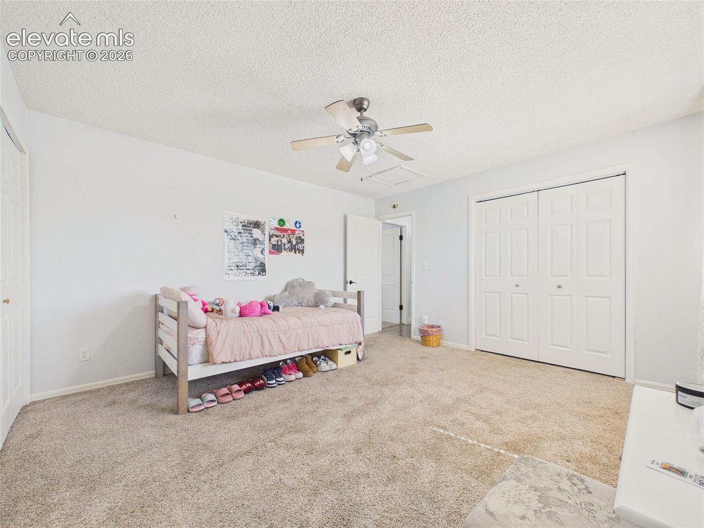 Spacious secondary bedroom provides comfortable carpeting, a ceiling fan, and expansive double-door closet storage.