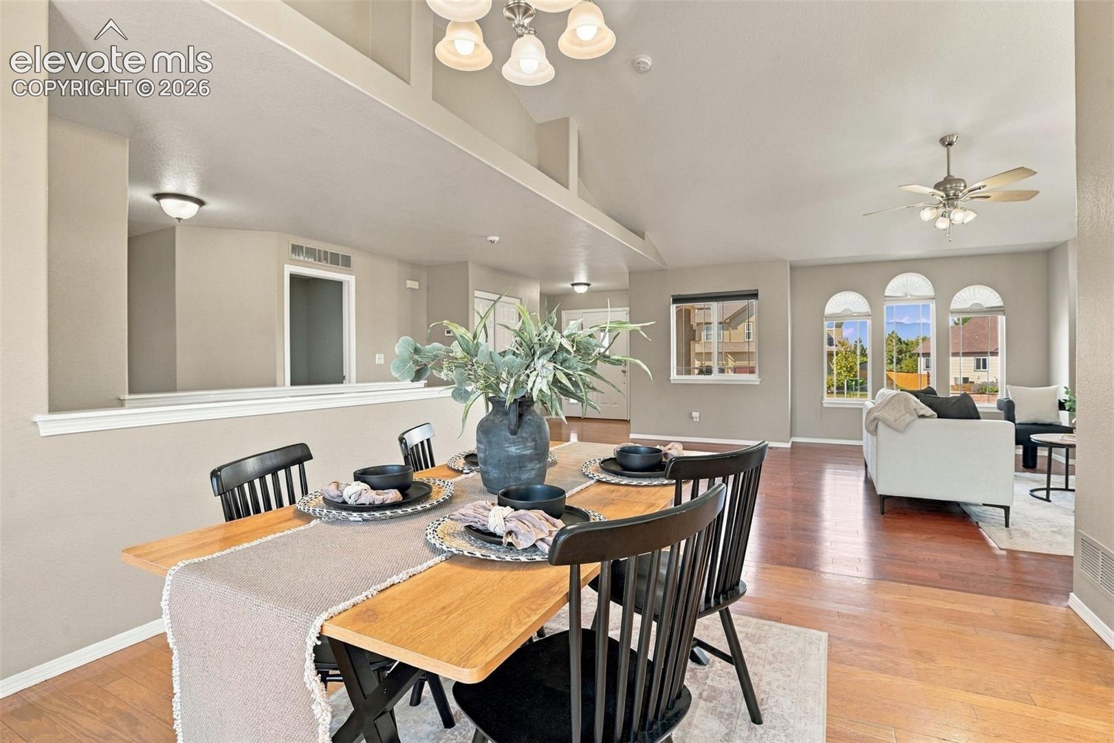 Open-concept living space with vaulted ceilings, wood-finish flooring, and arched windows