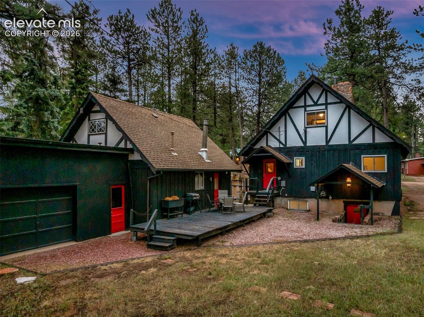 Showing the back of the property, with a deck, separate entrance to the 3rd bay, door entrance to the 2 bay garage, separate door entrance to the main house and separate entrance to the basement.