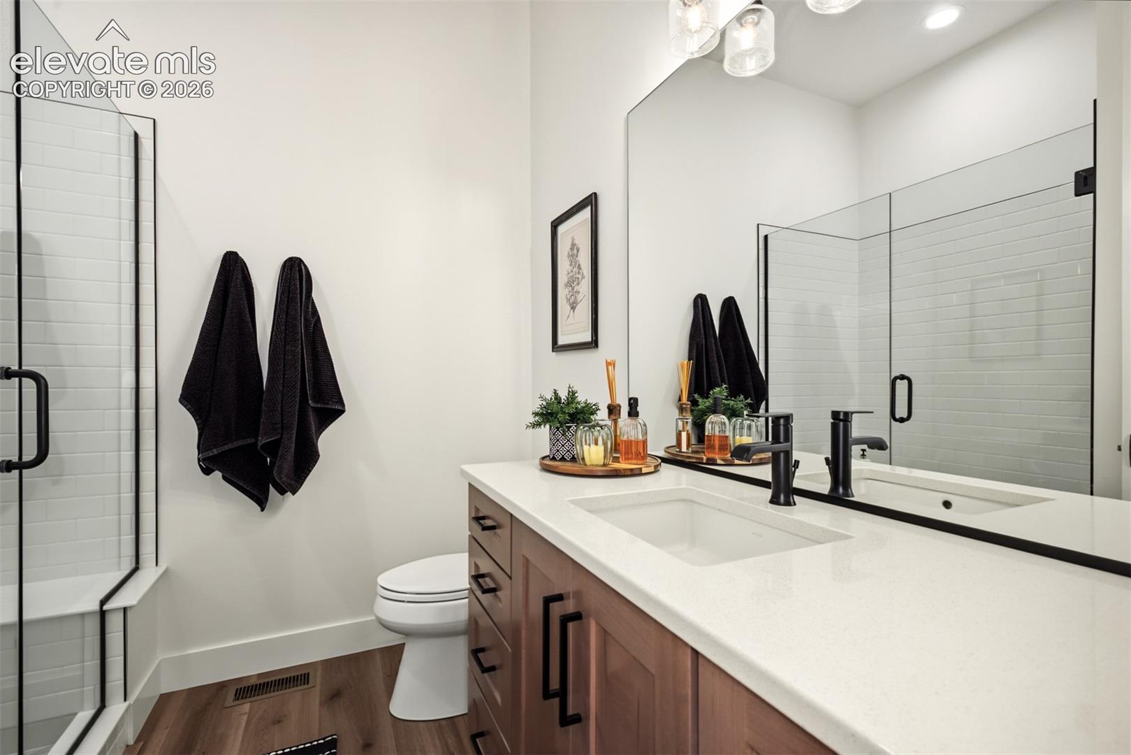 Beautifully appointed main-level bathroom featuring a spacious vanity, modern fixtures, and a glass-enclosed shower.