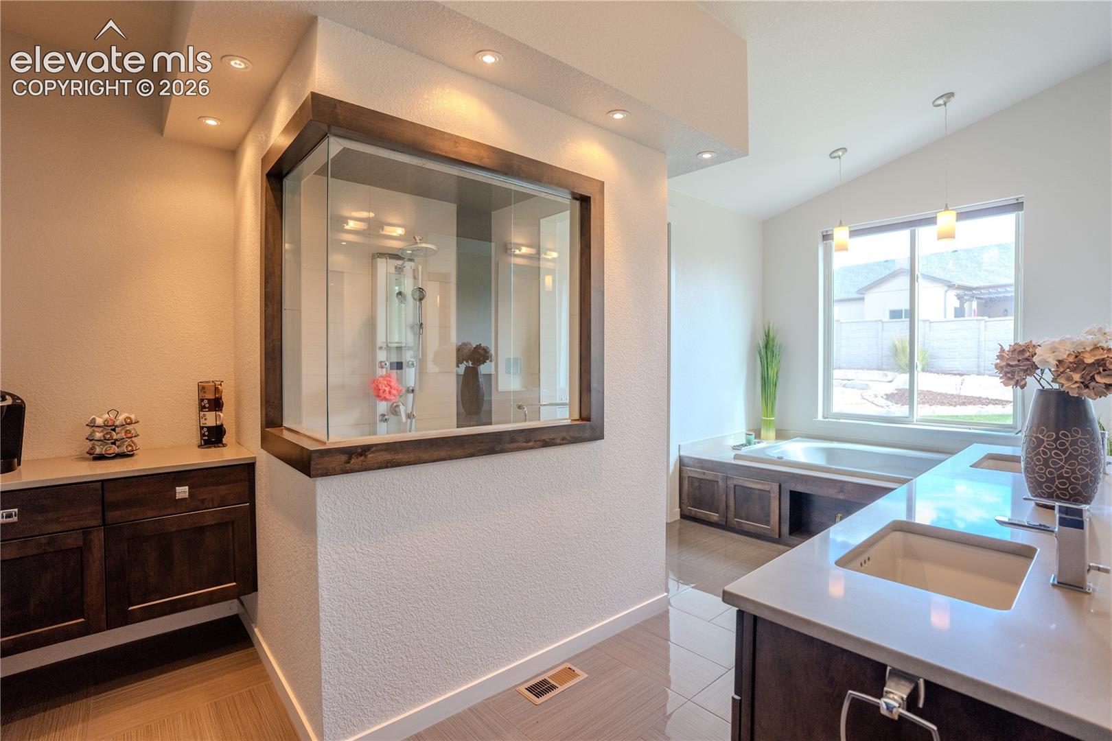 View of walk in steam shower, coffee bar, double vanity and jetted tub