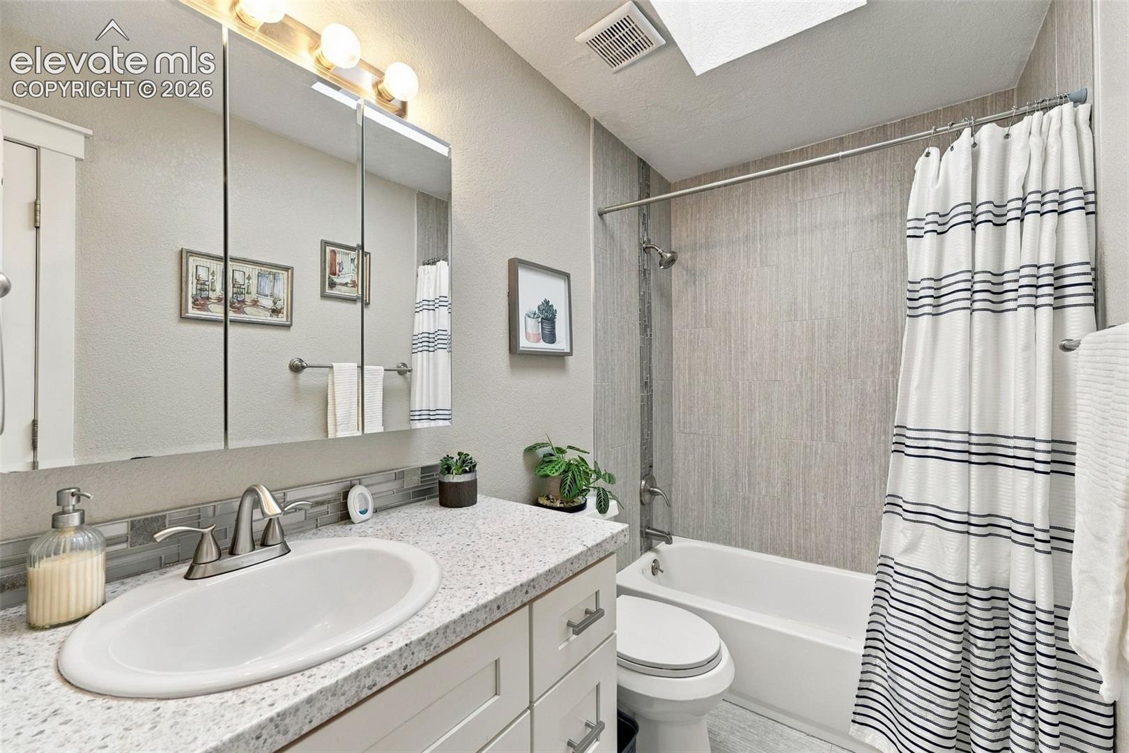 Built-in vanity with a speckled countertop, undermount sink, and brushed nickel faucet