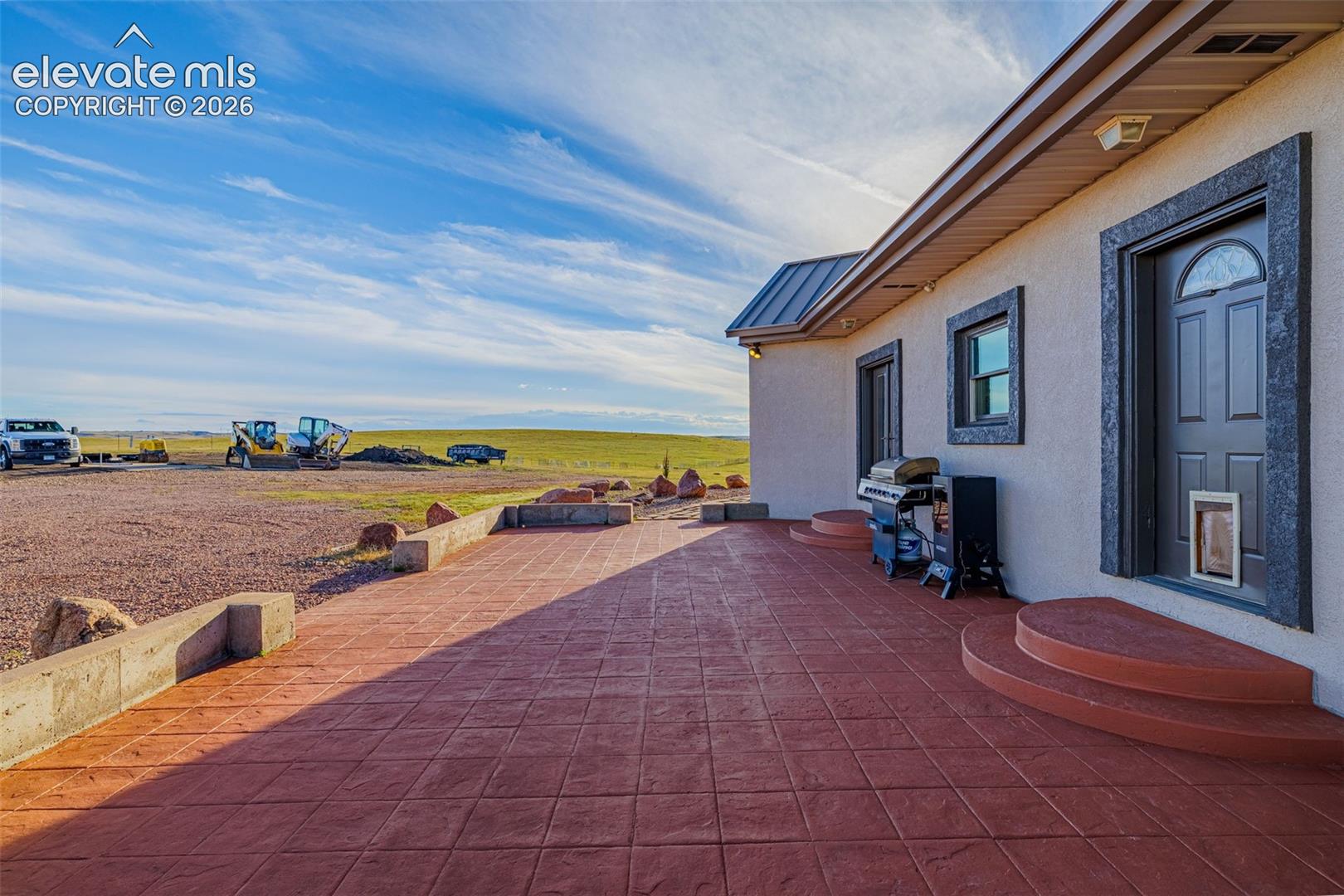 Stamped concrete patio with integrated steps, stucco exterior, and dark trim windows and doors