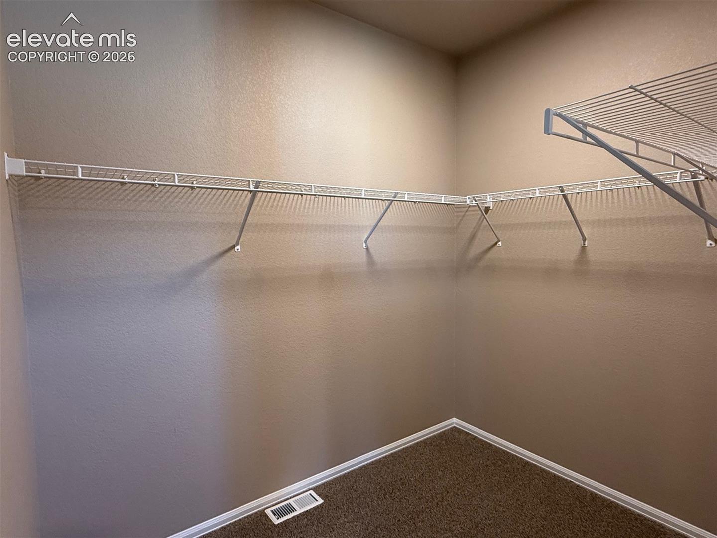 L-shaped wire shelving system, painted walls, and carpet flooring