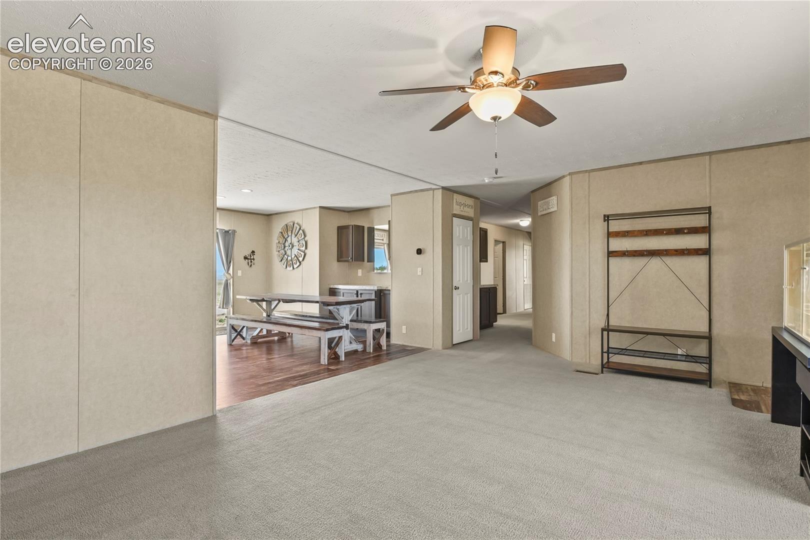 Neutral wall paneling, ceiling fan with integrated lighting, wood-finish flooring, and recessed interior door