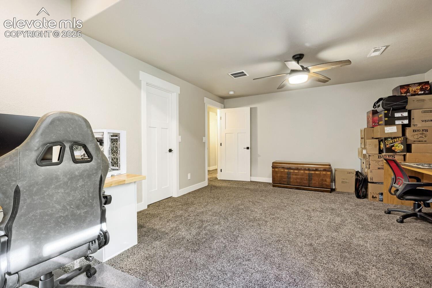 Carpeted room with a ceiling fan, white paneled doors, and light-toned walls