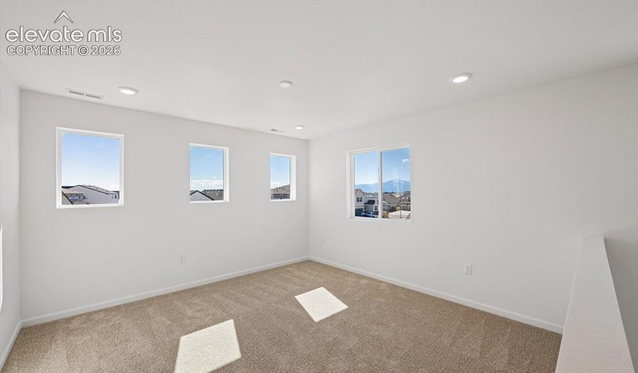 Spacious room featuring neutral carpeting, recessed ceiling lighting, and multiple windows