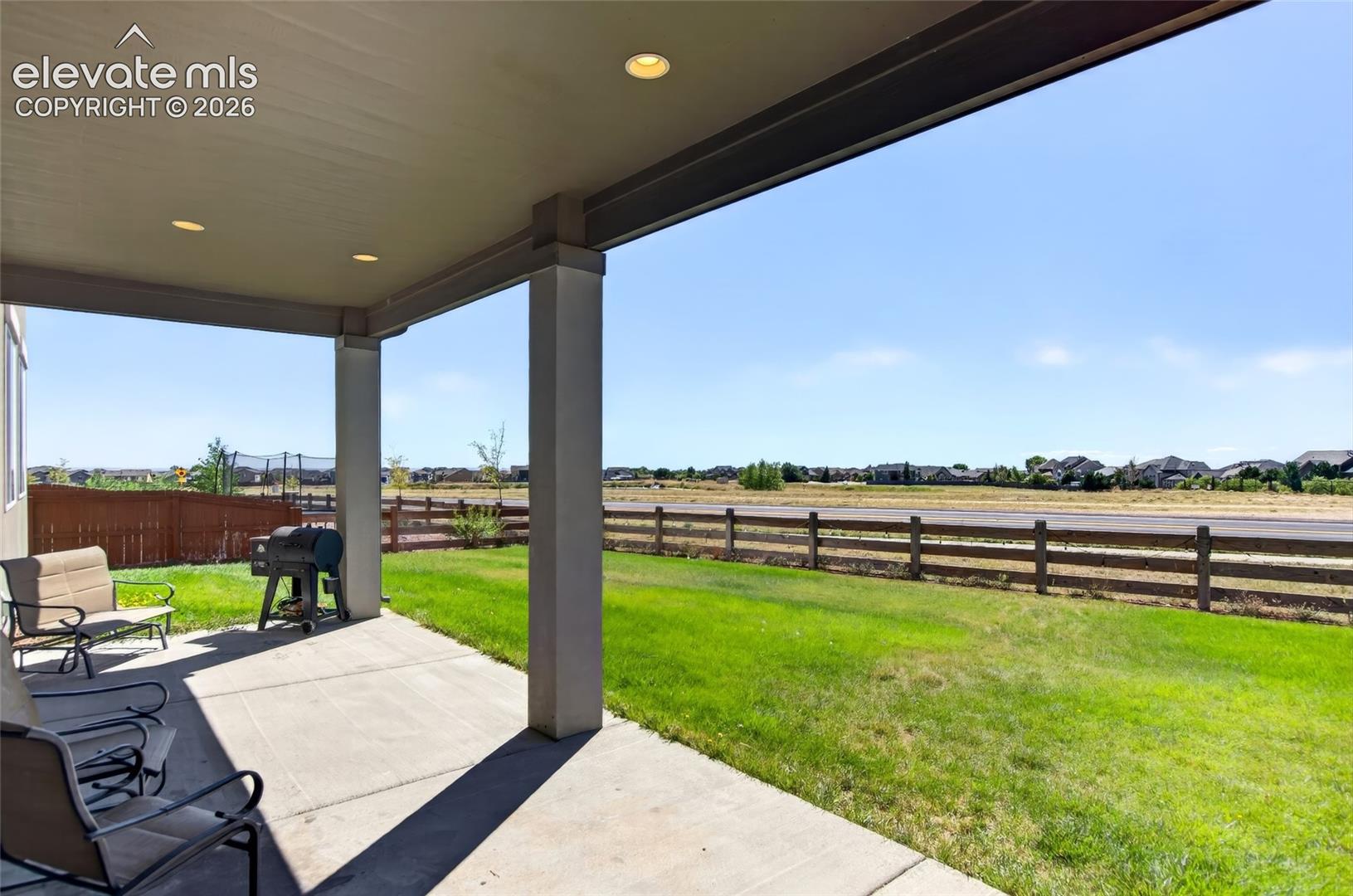 Covered patio featuring recessed lighting, concrete flooring, and direct access to a grassy yard with a wooden fence