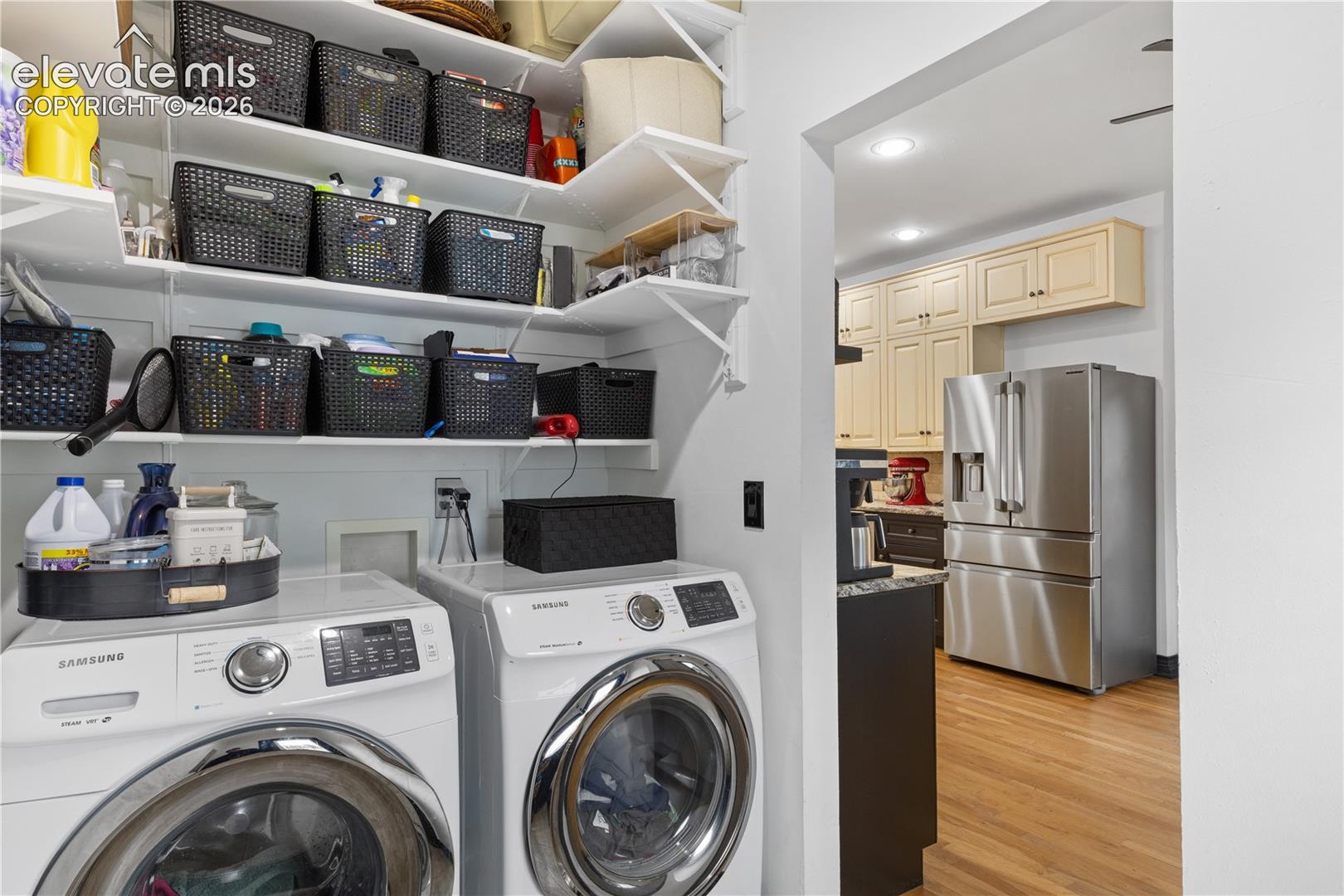 Dedicated laundry area featuring front-loading machines and extensive built-in shelving
