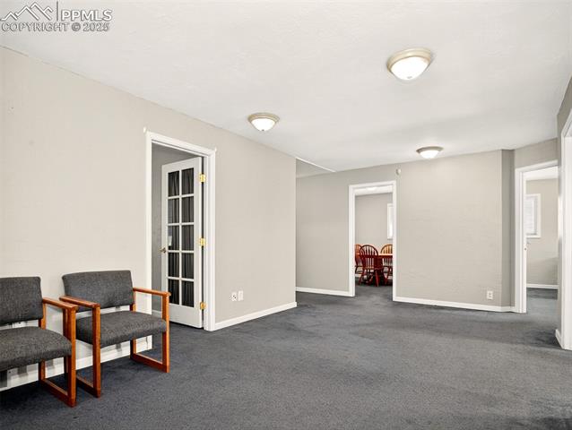Sitting room with dark carpet and baseboards