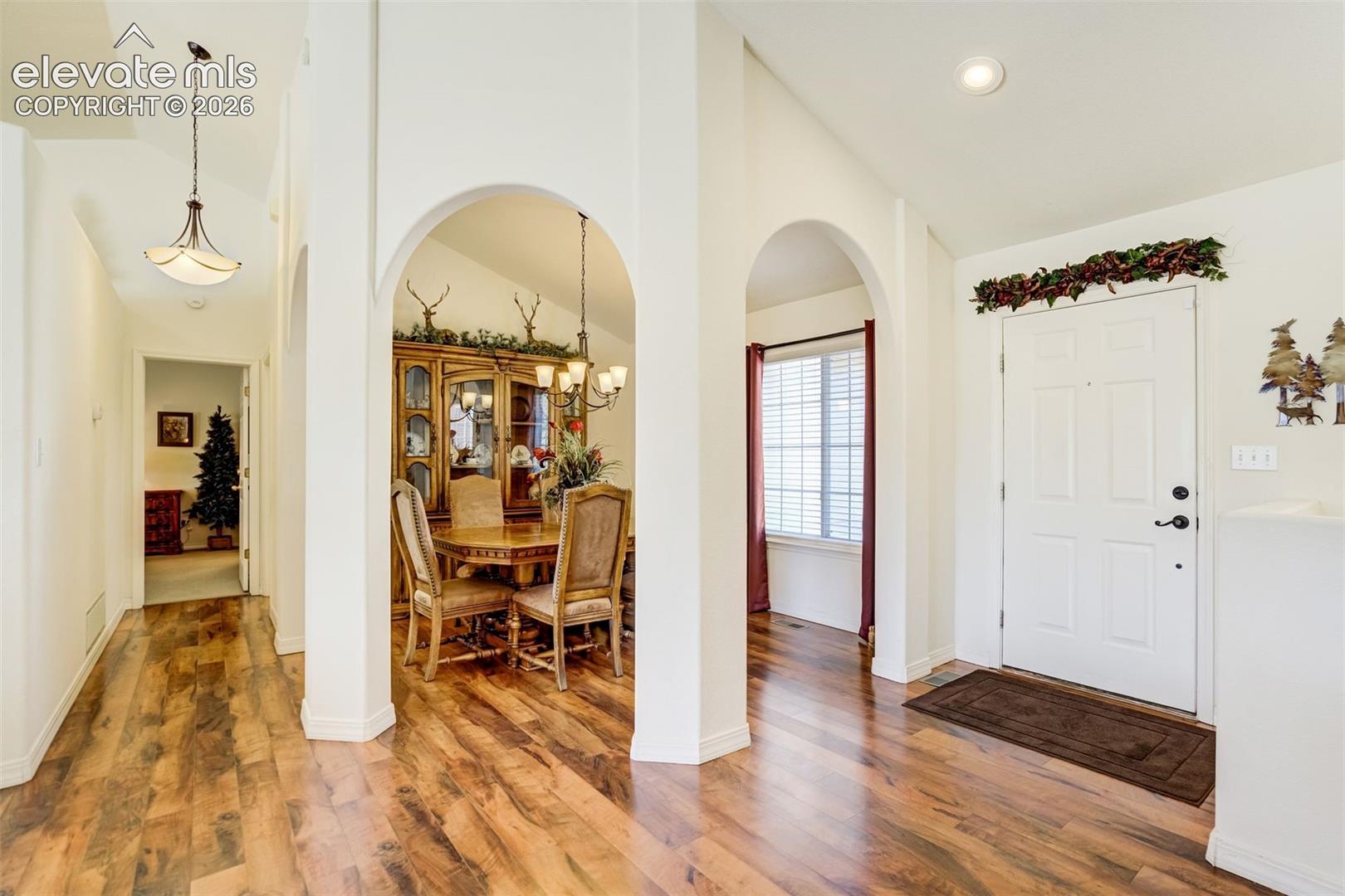 Entryway featuring vaulted ceilings, wood-finish flooring, recessed lighting, and dual decorative archways