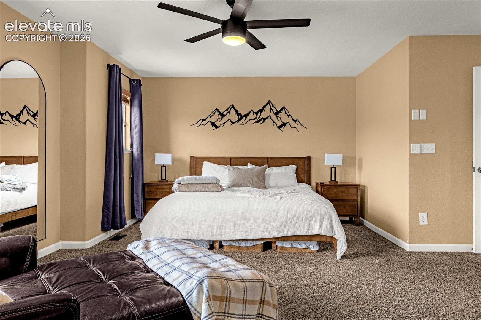 Spacious room featuring neutral wall paint, carpeting, an arched floor mirror, and a ceiling fan with integrated lighting