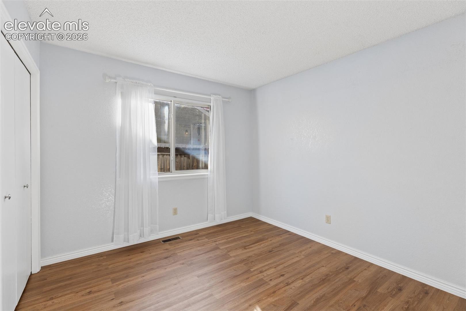 Room featuring wood-finish flooring, a horizontal sliding window, and a built-in closet with dual doors
