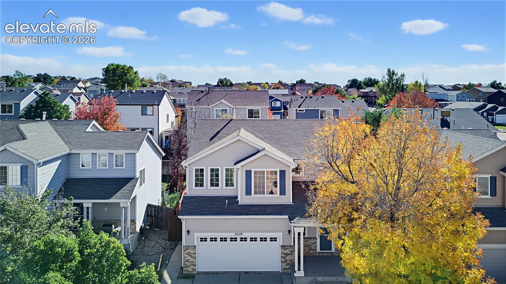 Two-story exterior featuring lap siding, stone veneer accents, a multi-paneled garage door, and a covered entry