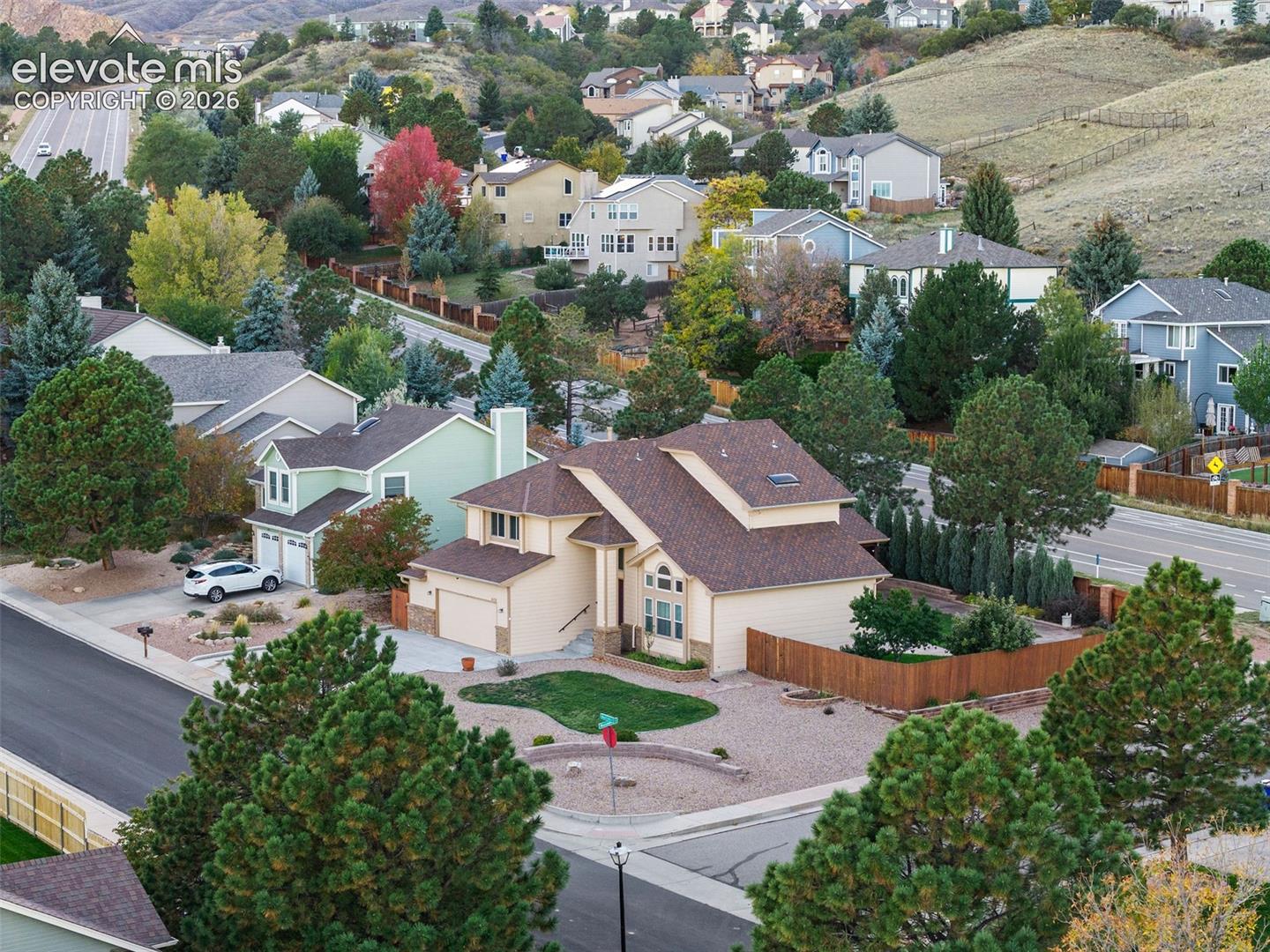 Two-story residence featuring shingled roofing, an attached garage, xeriscaped front yard with retaining wall, and wood privacy fencing