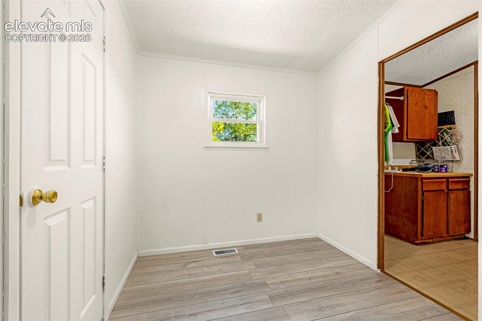 Interior space featuring wood-finish flooring, a six-panel door with brass-tone hardware, and a single-pane window