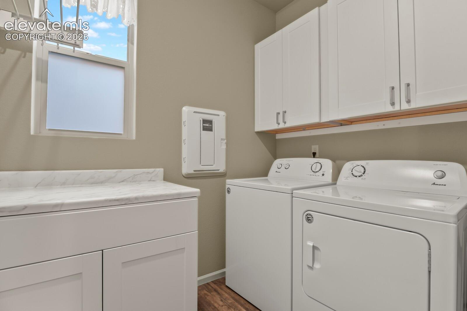 7'x6' Laundry area featuring custom white cabinetry, stone-finish countertops, wood-finish flooring, and wall-mounted drying rack
