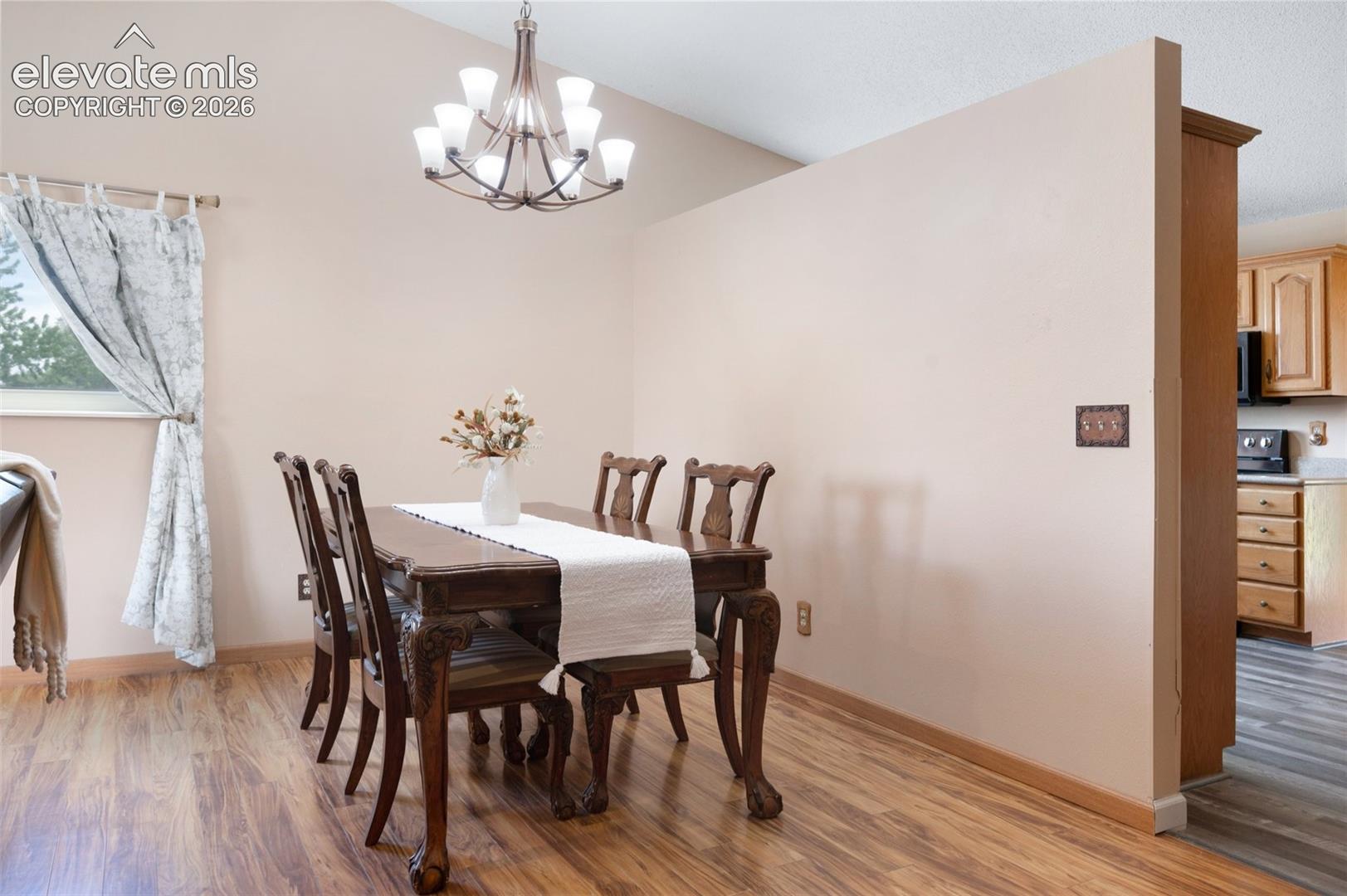Dining room featuring a chandelier, light wood-type flooring, and baseboards