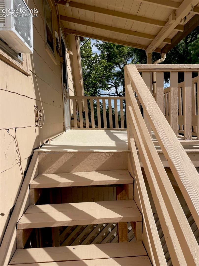 Covered porch with wooden stairs and railing