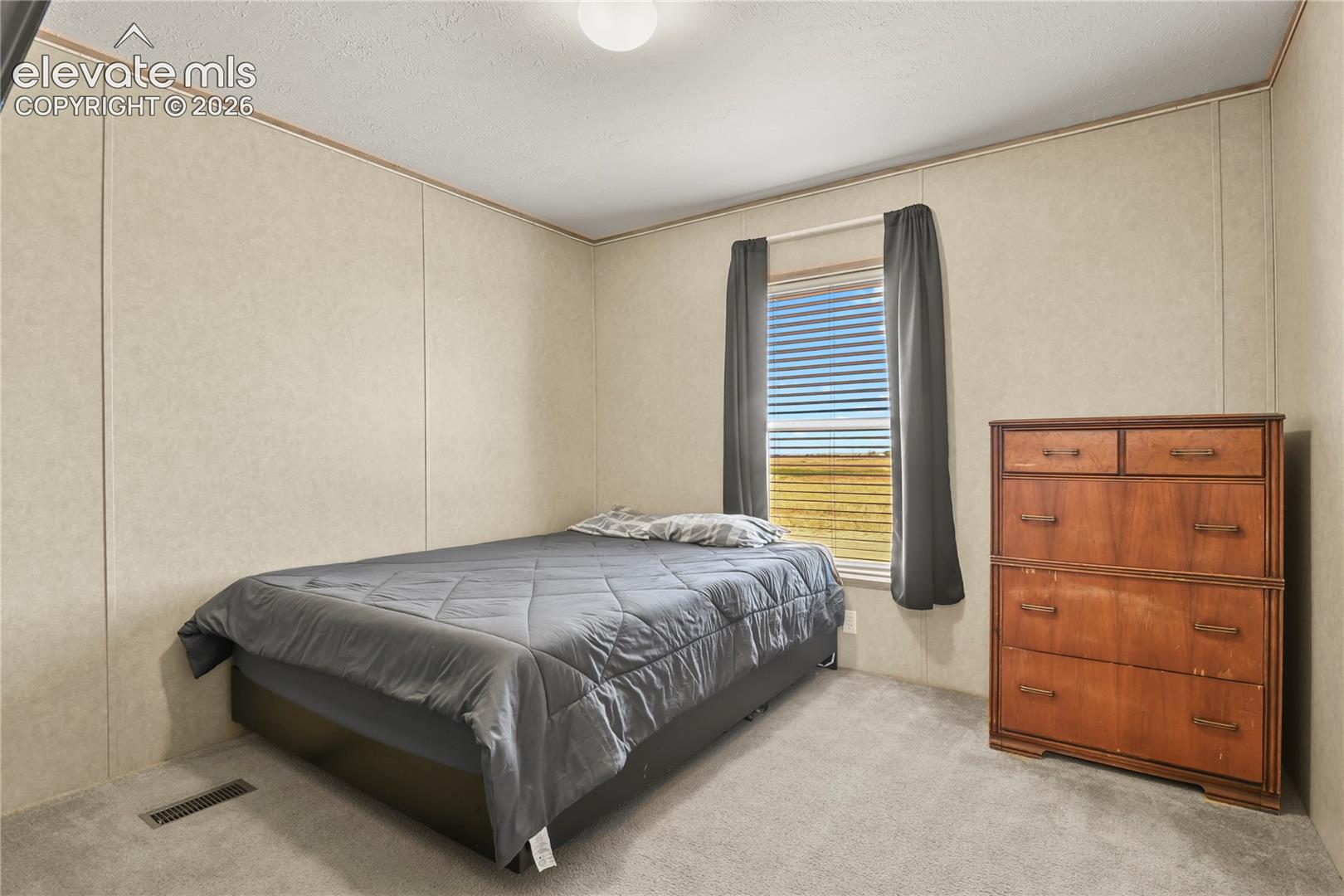 Neutral-toned panel walls, wall-to-wall carpeting, and a window with a natural landscape outlook