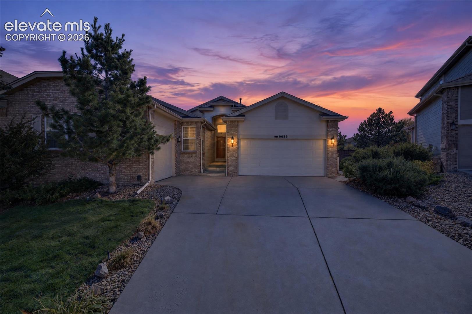 Multi-gabled exterior featuring stone masonry accents, stucco siding, a concrete driveway, and an attached multi-car garage
