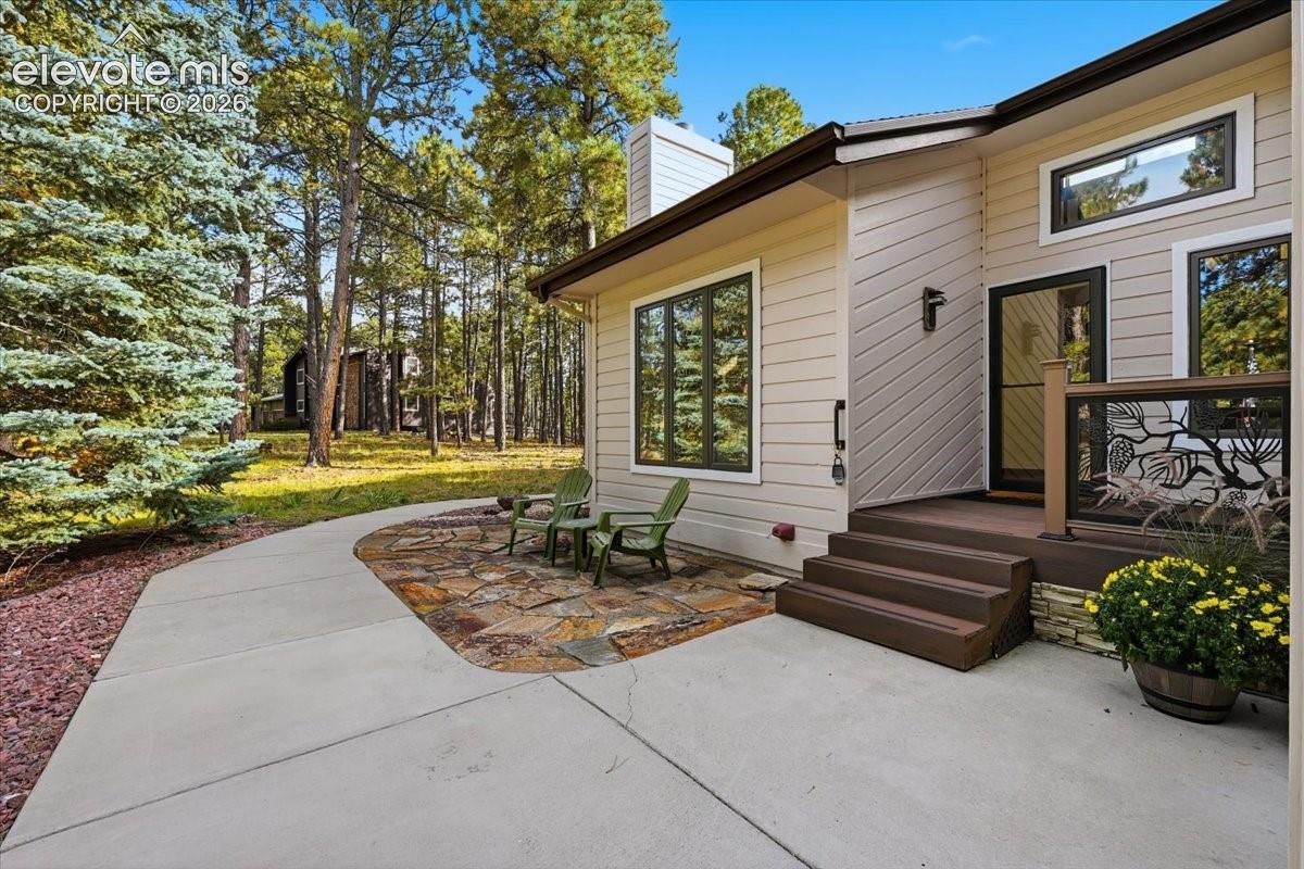 Exterior siding, multi-pane windows, wood-finish porch with railing, stone accent wall, and concrete pathway