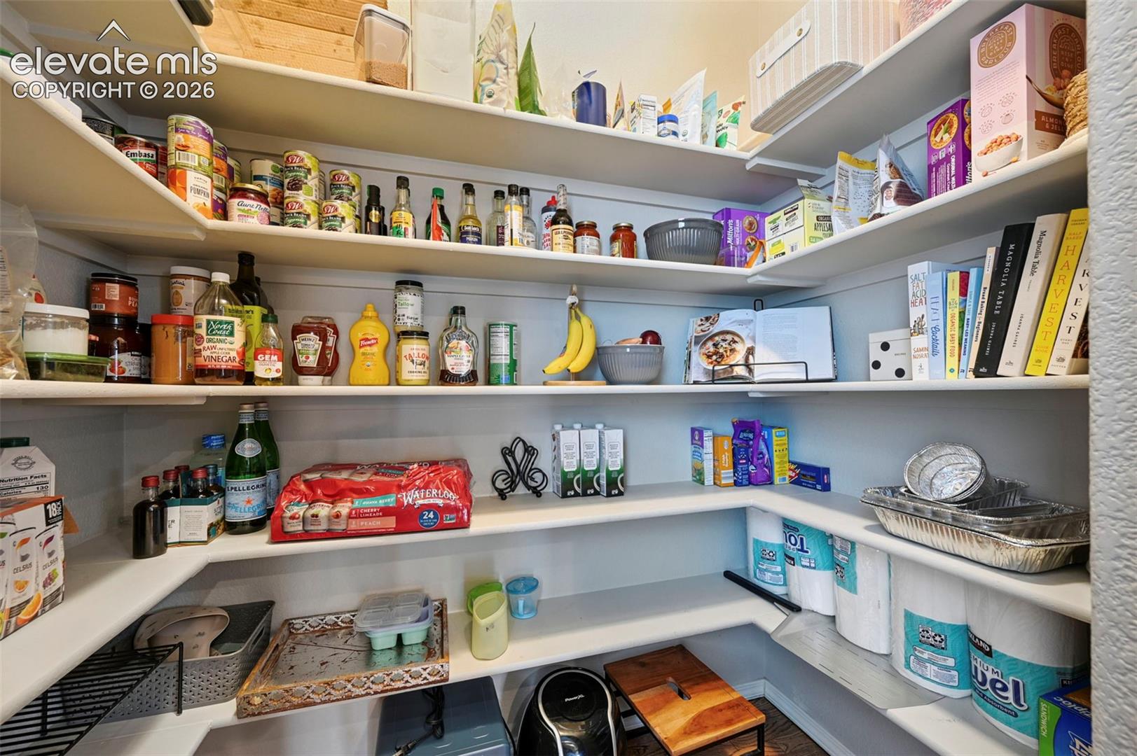 Walk-in pantry featuring expansive multi-level white shelving and shiplap wall detailing